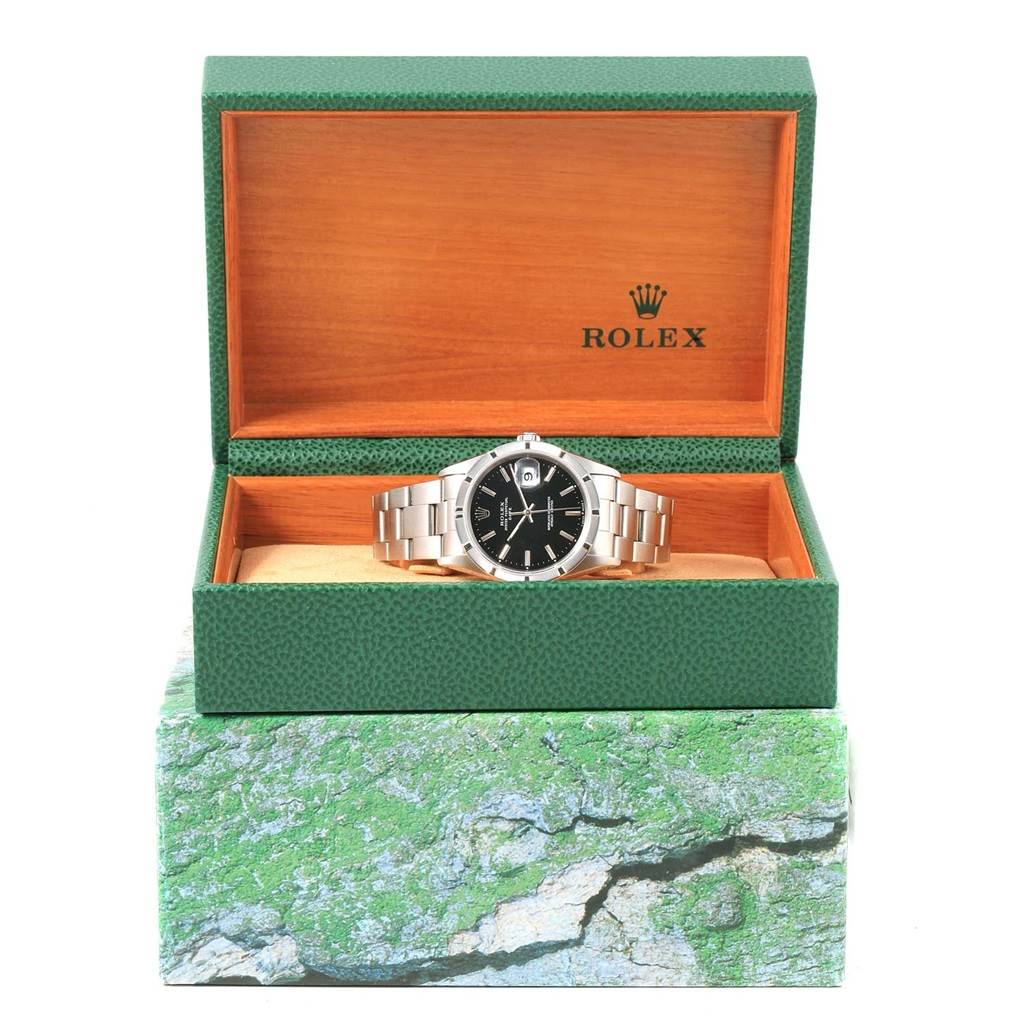 The Rolex Date 15210 Men's Stainless Steel Black Dial 15210 Men's Stainless Steel Black Dial model watch is shown front-facing inside an open green and wooden Rolex box.