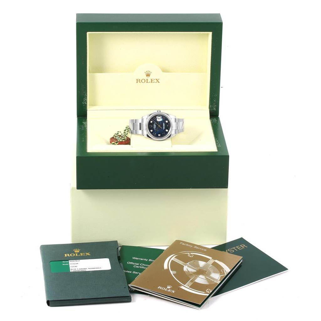 This image shows a Rolex Date 115234 Stainless Steel Blue Dial 115234 Stainless Steel Blue Dial model watch in its box with accompanying booklets and tags, viewed from the front.