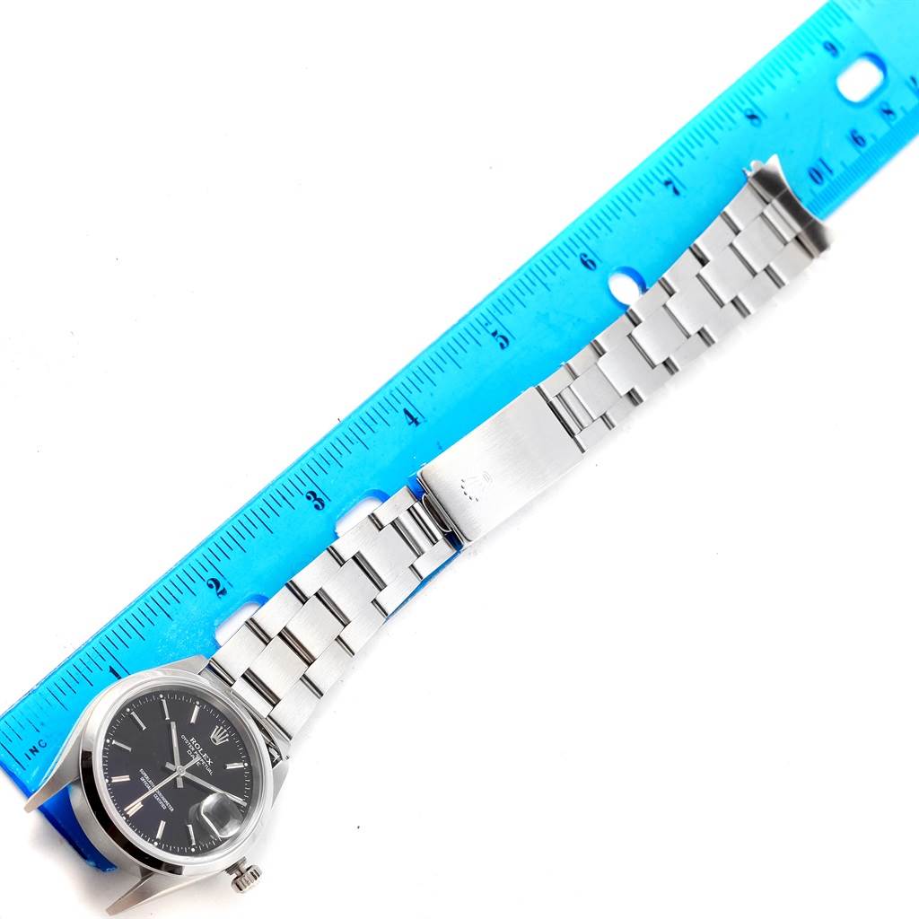 The image shows a Rolex Date 15200 Men's Stainless Steel Black Dial 15200 Men's Stainless Steel Black Dial watch with a silver bracelet, clasp, and black dial, laid next to a blue ruler for measurement.