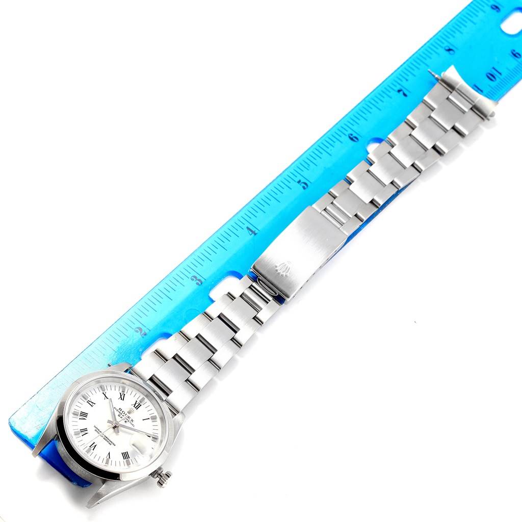 The image shows a Rolex Date 15200 Men's Stainless Steel White Dial 15200 Men's Stainless Steel White Dial model watch laid flat next to a blue ruler, highlighting its bracelet and clasp.