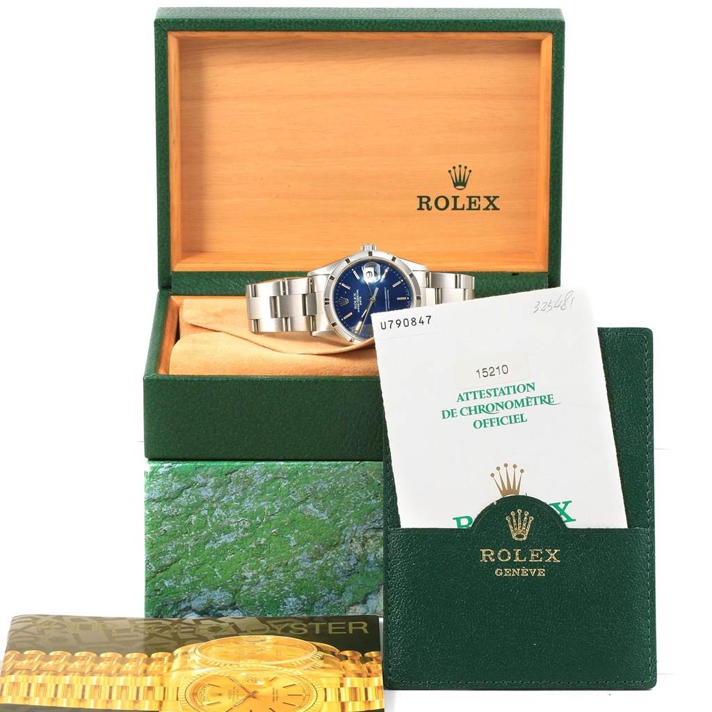 The Rolex Date 15210 Men's Stainless Steel Blue Dial 15210 Men's Stainless Steel Blue Dial model watch is shown in a frontal view inside its open box, along with its booklet and certification.