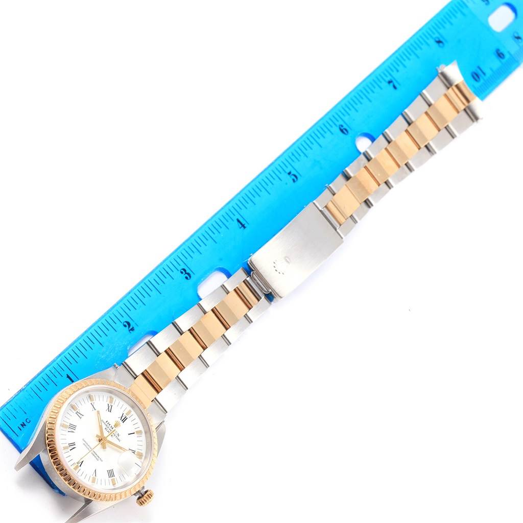 The image shows a Rolex Date 15223 Men's Steel and Gold (two tone) White Dial 15223 Men's Steel and Gold (two tone) White Dial model watch lying flat alongside a blue ruler, capturing the dial, bezel, and the two-tone bracelet.