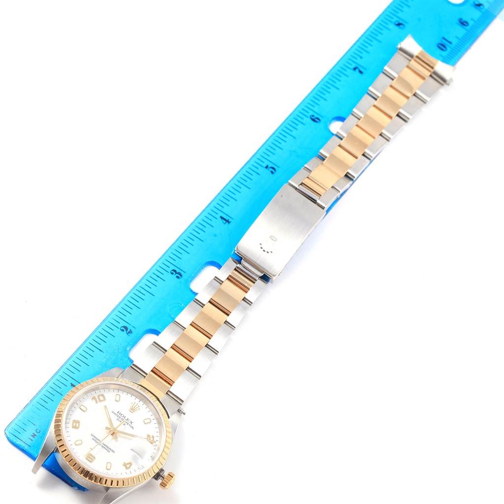 The image shows a Rolex Date 15223 Men's Steel and Gold (two tone) White Dial 15223 Men's Steel and Gold (two tone) White Dial model watch laid flat next to a blue ruler, displaying the face, bezel, and two-tone bracelet.