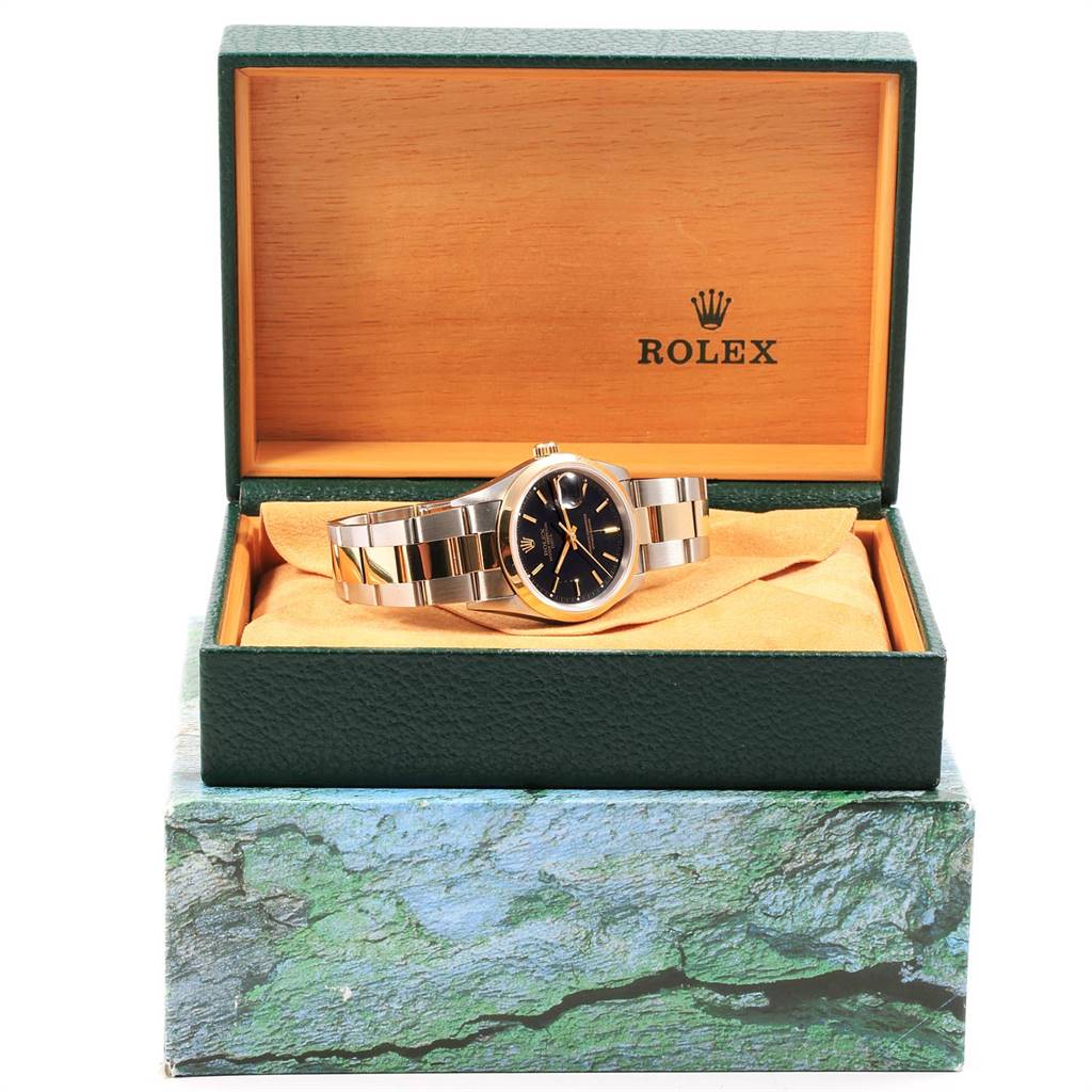 The Rolex Date 15203 Men's Steel and Gold (two tone) Black Dial 15203 Men's Steel and Gold (two tone) Black Dial model watch is displayed at a front angle inside an open green and wood-colored box with the Rolex logo.