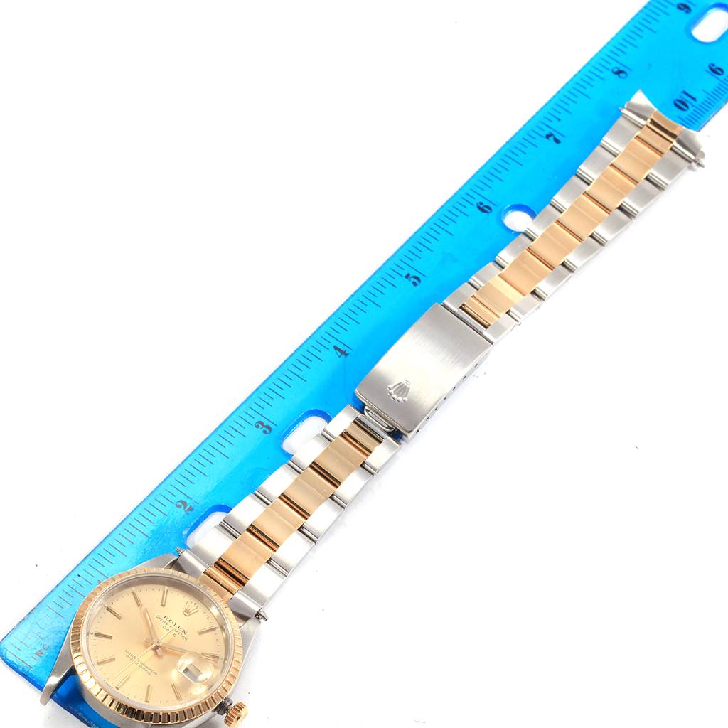 The Rolex Date 15223 Men's Steel and Gold (two tone) Champagne Dial 15223 Men's Steel and Gold (two tone) Champagne Dial watch is shown from a top-down angle, highlighting the dial, fluted bezel, and two-tone bracelet with clasp.