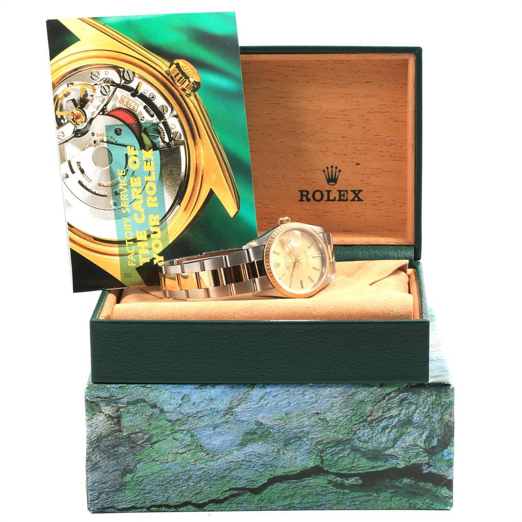 The Rolex Date 15223 Men's Steel and Gold (two tone) Champagne Dial 15223 Men's Steel and Gold (two tone) Champagne Dial model watch is shown inside its open box with a service booklet displayed.