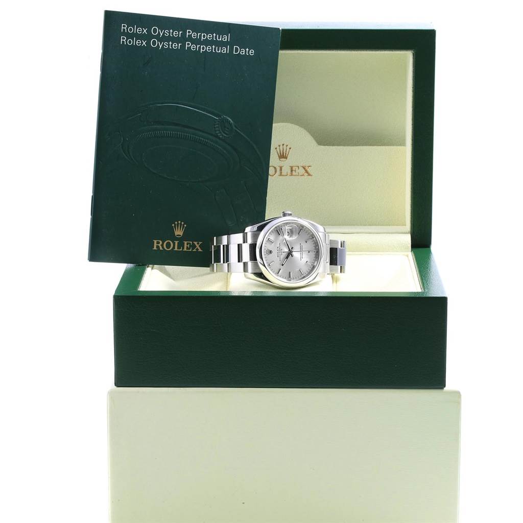 The image shows a Rolex Date 115200 Men's Stainless Steel Silver Dial 115200 Men's Stainless Steel Silver Dial model watch in its open box, with a booklet propped against the box lid.