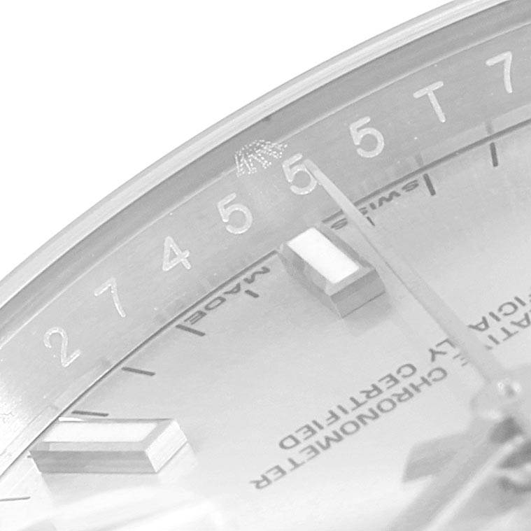 This angled shot of the Rolex Date 115200 Men's Stainless Steel Silver Dial 115200 Men's Stainless Steel Silver Dial model shows part of the dial with hour markers and part of the watch hands, magnifying some details.
