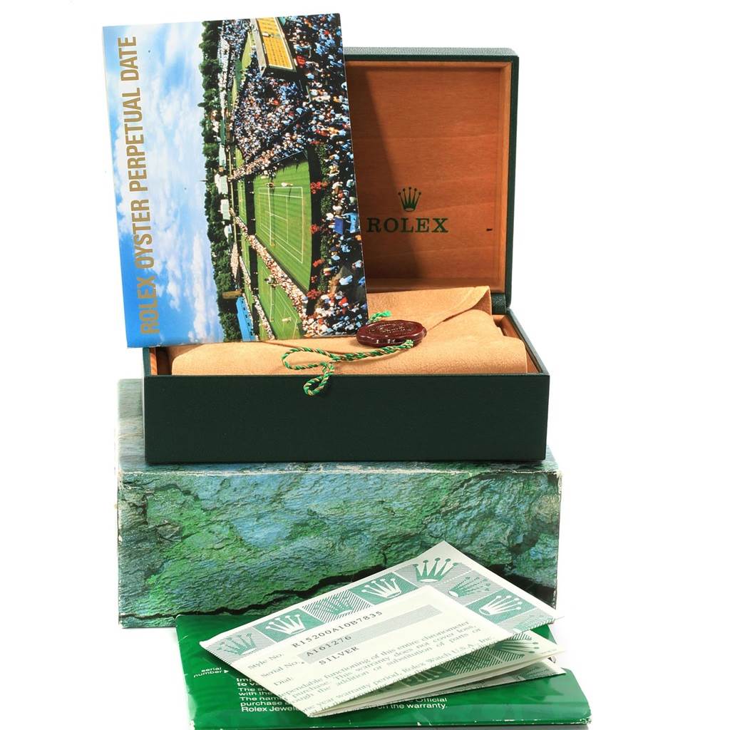 The image shows the packaging and accessories for a Rolex Oyster Perpetual Date model, including a booklet, tags, and warranty papers.