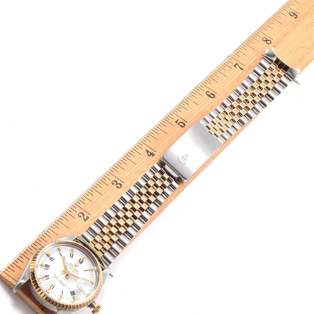 This image shows the Rolex Date 15053 Men's Steel and Gold (two tone) White Dial 15053 Men's Steel and Gold (two tone) White Dial model watch laid flat next to a ruler, highlighting its face, bracelet, and clasp.