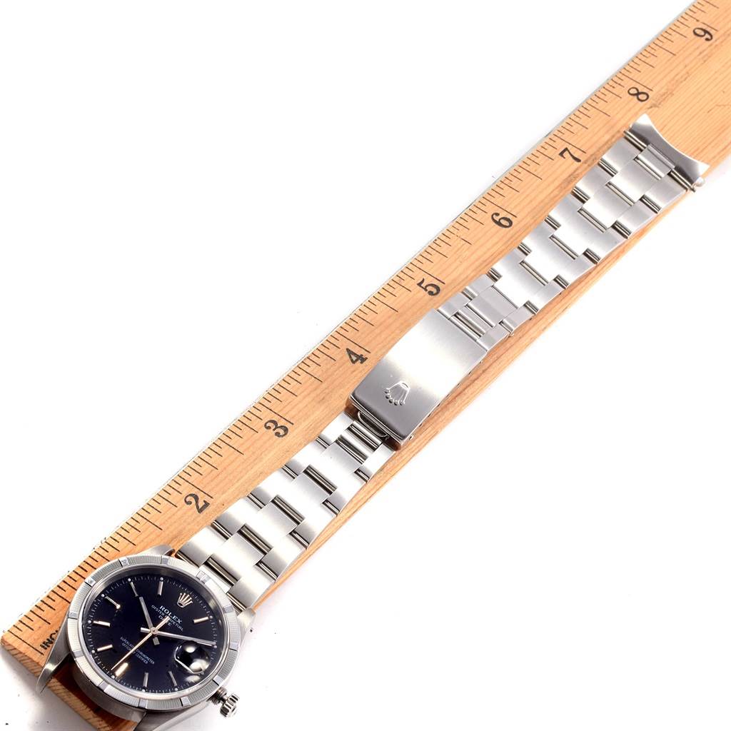 The image shows a Rolex Date 15210 Men's Stainless Steel Black Dial 15210 Men's Stainless Steel Black Dial model watch laid flat alongside a wooden ruler, displaying the watch face and stainless steel bracelet.