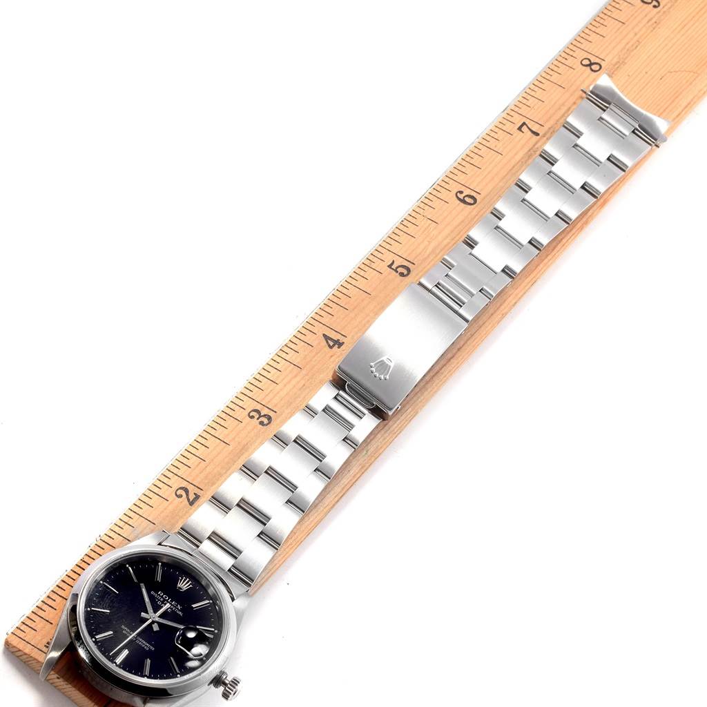 The image shows a top-down view of a Rolex Date 15200 Men's Stainless Steel Black Dial 15200 Men's Stainless Steel Black Dial watch, focused on its face and metal bracelet, alongside a ruler for measurement.