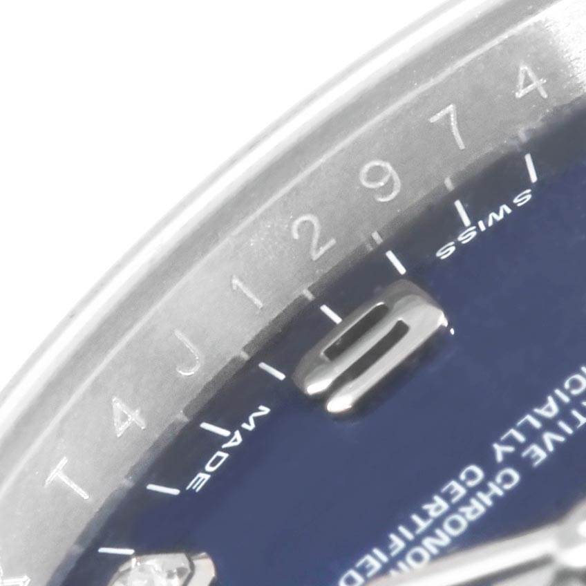 The image shows a close-up of the upper half of a blue Rolex Date 115234 Men's Stainless Steel Blue Dial 115234 Men's Stainless Steel Blue Dial model watch, highlighting the dial, bezel, and part of an hour marker.
