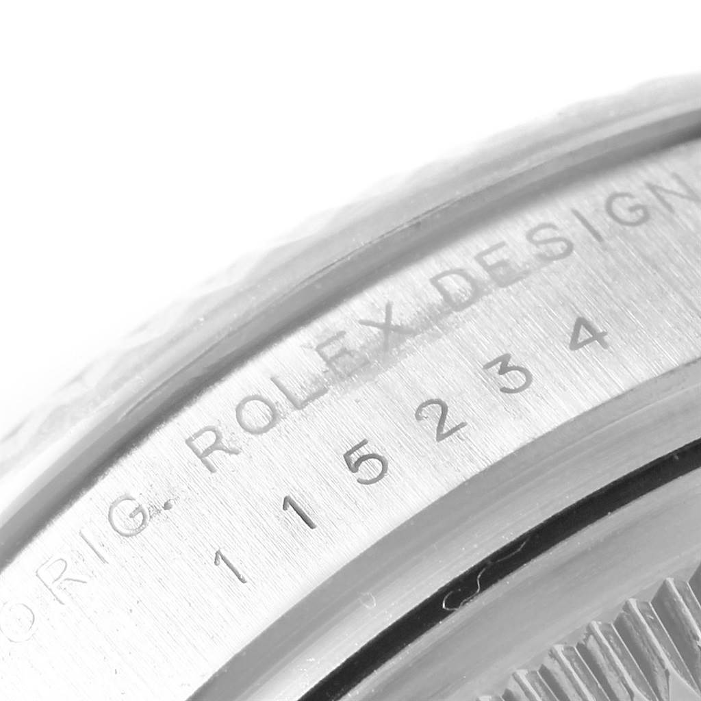 The image shows a close-up of the case back with the engraved serial number of a Rolex Date 115234 Men's Stainless Steel Blue Dial 115234 Men's Stainless Steel Blue Dial model watch.