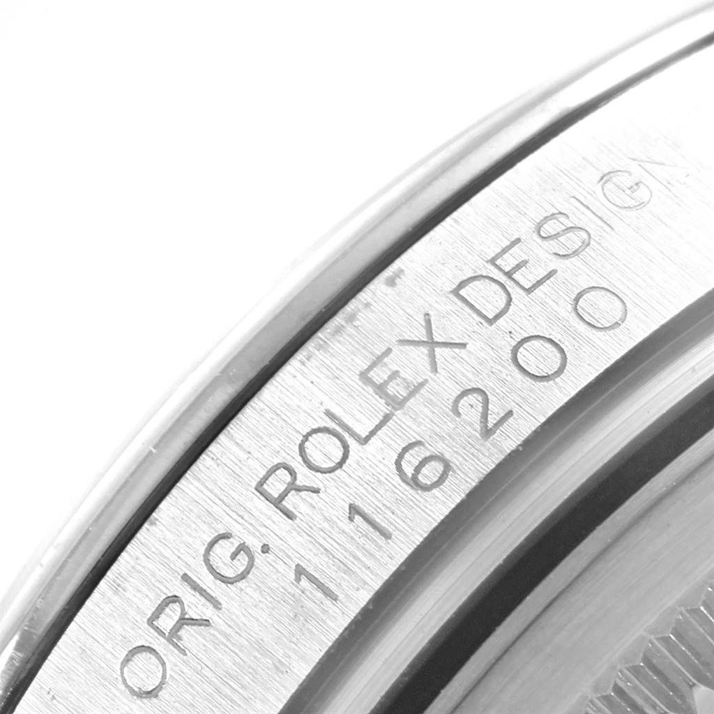 This is a close-up of the engraved side edge of a Rolex Date 116200 Men's Stainless Steel Black Dial 116200 Men's Stainless Steel Black Dial model watch, showing the model number and design details.