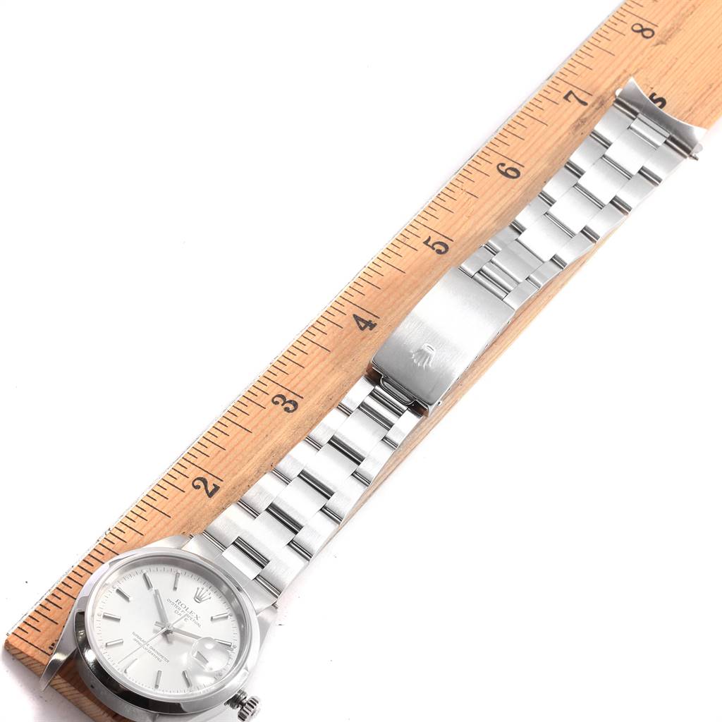 The image shows a Rolex Date 15200 Men's Stainless Steel Silver Dial 15200 Men's Stainless Steel Silver Dial model watch from a top-down angle, displaying the face, bracelet, and clasp next to a ruler for scale.