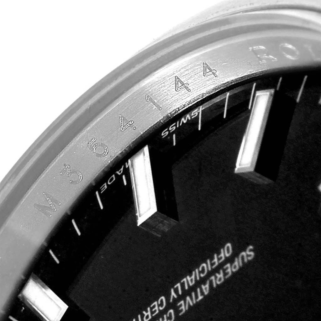 This close-up image of a Rolex Date 115200 Men's Stainless Steel Black Dial 115200 Men's Stainless Steel Black Dial model shows the dial edge with hour markers and partially visible text.