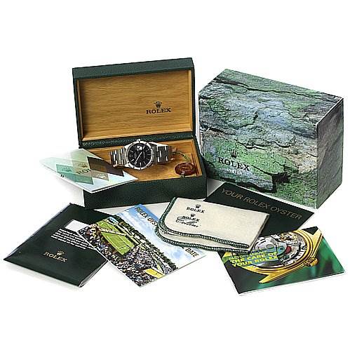 The image shows a Rolex Date 15210 Men's Stainless Steel Black Dial 15210 Men's Stainless Steel Black Dial watch from a front angle, along with its box, warranty card, manuals, and cloth.