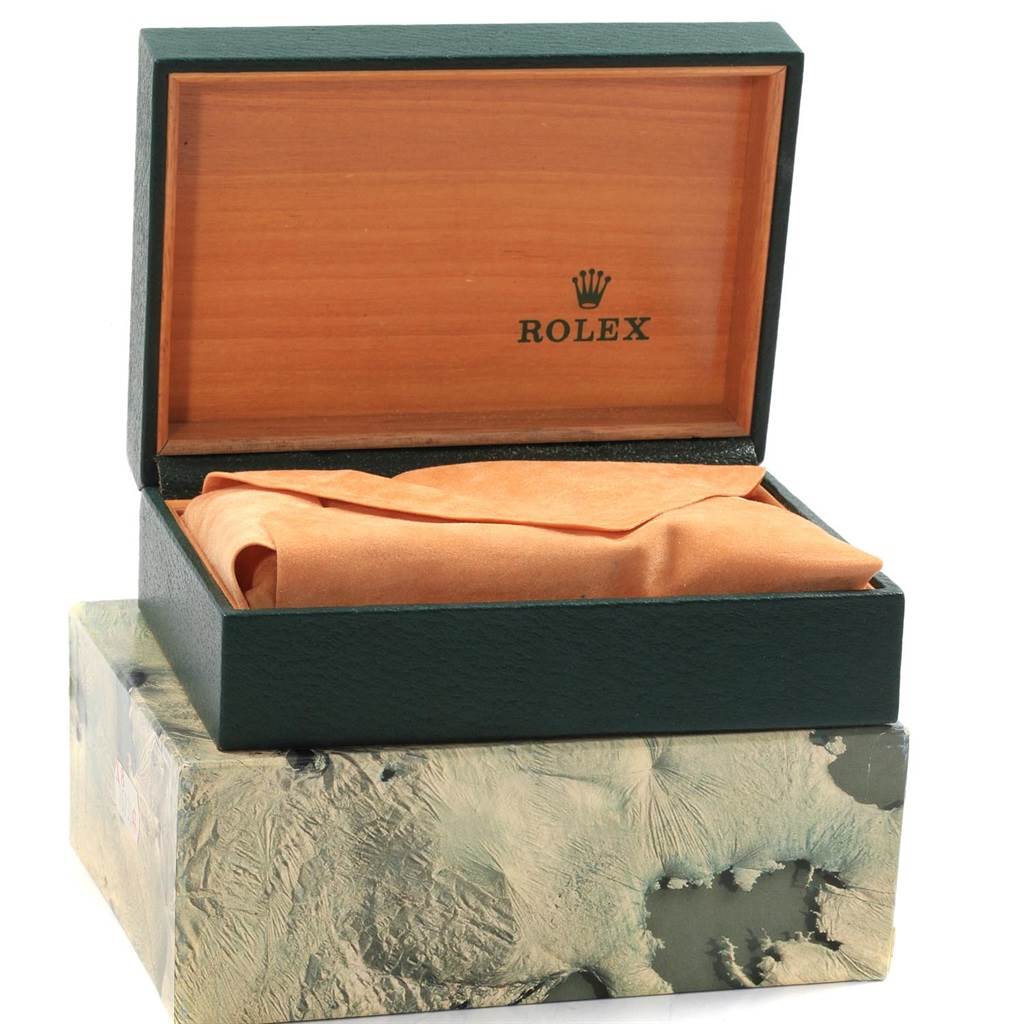 The image shows an open wooden box from Rolex with a Date model watch inside, covered by a cloth.
