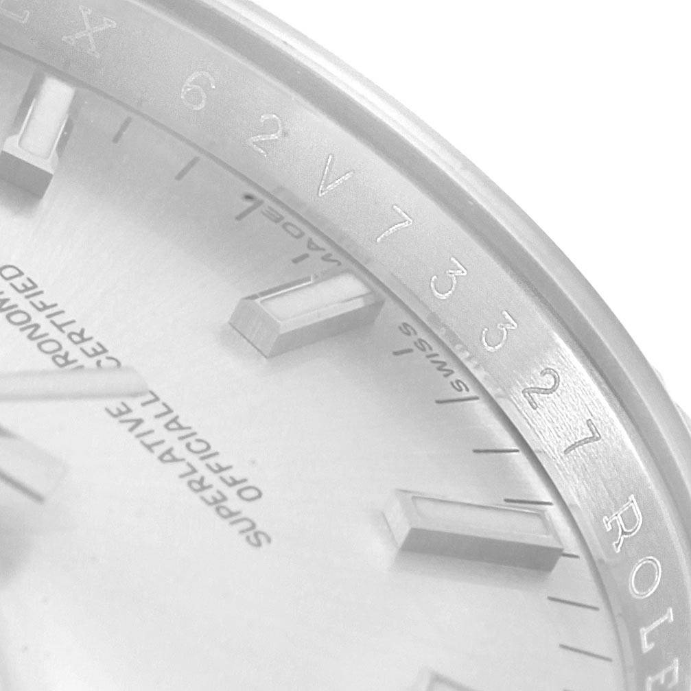 This close-up image of a Rolex Date 115234 Men's Stainless Steel Silver Dial 115234 Men's Stainless Steel Silver Dial watch shows the partial dial and bezel, highlighting some hour markers, engravings, and text certification.