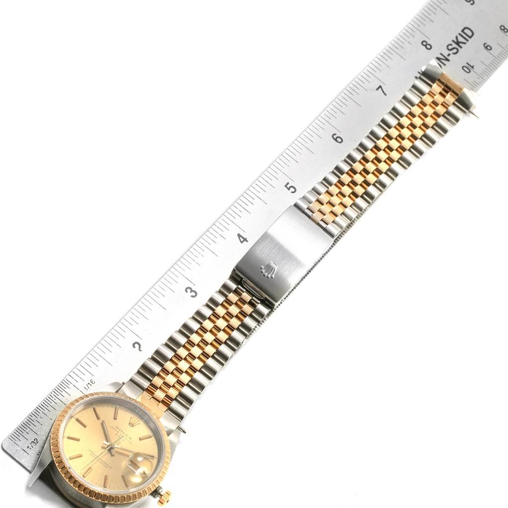 The image shows the front view of a Rolex Date 15223 Men's Steel and Gold (two tone) Champagne Dial 15223 Men's Steel and Gold (two tone) Champagne Dial watch with a measurement scale, displaying the watch face and the metal bracelet.