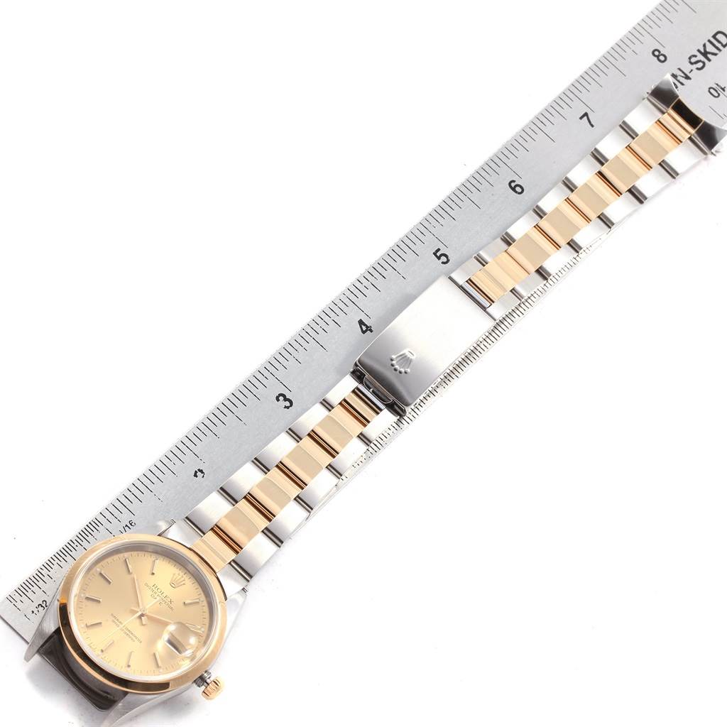 The image shows a top-down view of a Rolex Date 15203 Men's Steel and Gold (two tone) Champagne Dial 15203 Men's Steel and Gold (two tone) Champagne Dial model watch with a two-tone bracelet and a ruler for scale.
