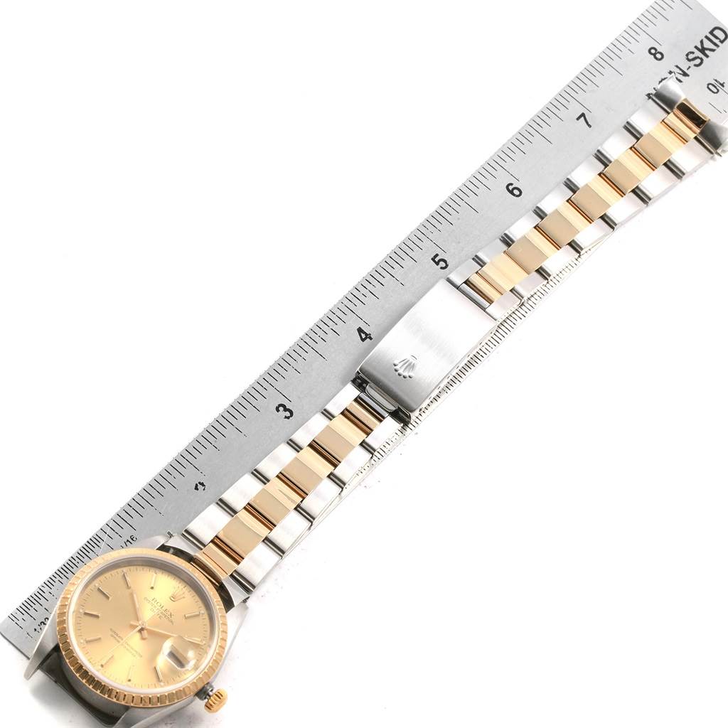 The image shows a Rolex Date 15223 Men's Steel and Gold (two tone) Champagne Dial 15223 Men's Steel and Gold (two tone) Champagne Dial watch from an overhead angle, including the dial, bracelet, and clasp next to a ruler.