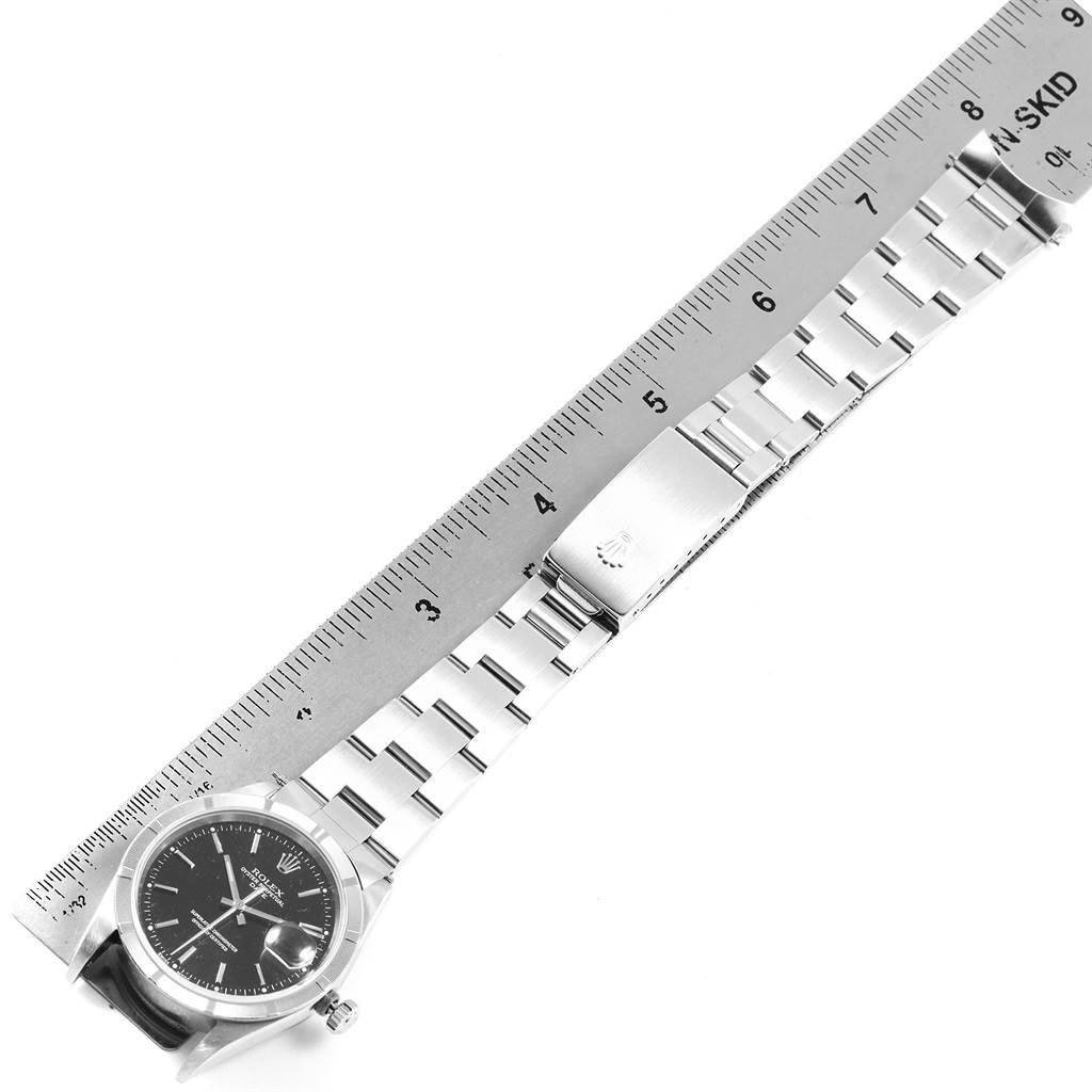 The image shows a top-down view of a Rolex Date 15210 Men's Stainless Steel Black Dial 15210 Men's Stainless Steel Black Dial model watch next to a ruler, highlighting the bracelet and clasp.