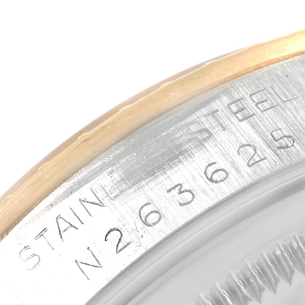 This close-up image shows the side of a Rolex Date 15223 Men's Steel and Gold (two tone) Champagne Dial 15223 Men's Steel and Gold (two tone) Champagne Dial model watch, highlighting the stainless steel case and part of the bezel with engravings.