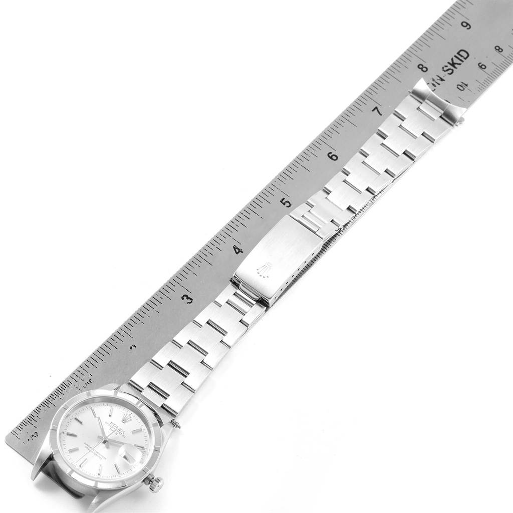 This image shows a Rolex Date 15210 Men's Stainless Steel Silver Dial 15210 Men's Stainless Steel Silver Dial model watch laid flat with its bracelet extended next to a ruler for measurement.