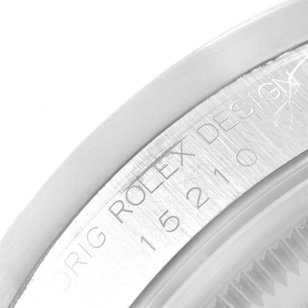 The image shows an angled close-up of the Rolex Date 15210 Men's Stainless Steel Silver Dial 15210 Men's Stainless Steel Silver Dial model's casing, featuring engraved text and part of the bezel.