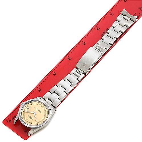 This image shows a Rolex Date 15010 Men
s Stainless Steel Champagne Dial 15010 Men
s Stainless Steel Champagne Dial model watch laid flat on a red ruler, displaying the entire watch, including the face, bracelet, and clasp.