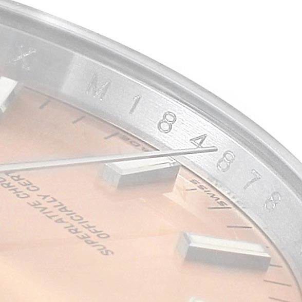 The image shows a close-up angle of the dial and bezel of a Rolex Date 115200 Men's Stainless Steel Pink Dial 115200 Men's Stainless Steel Pink Dial model watch, highlighting the serial number and part of its markers.
