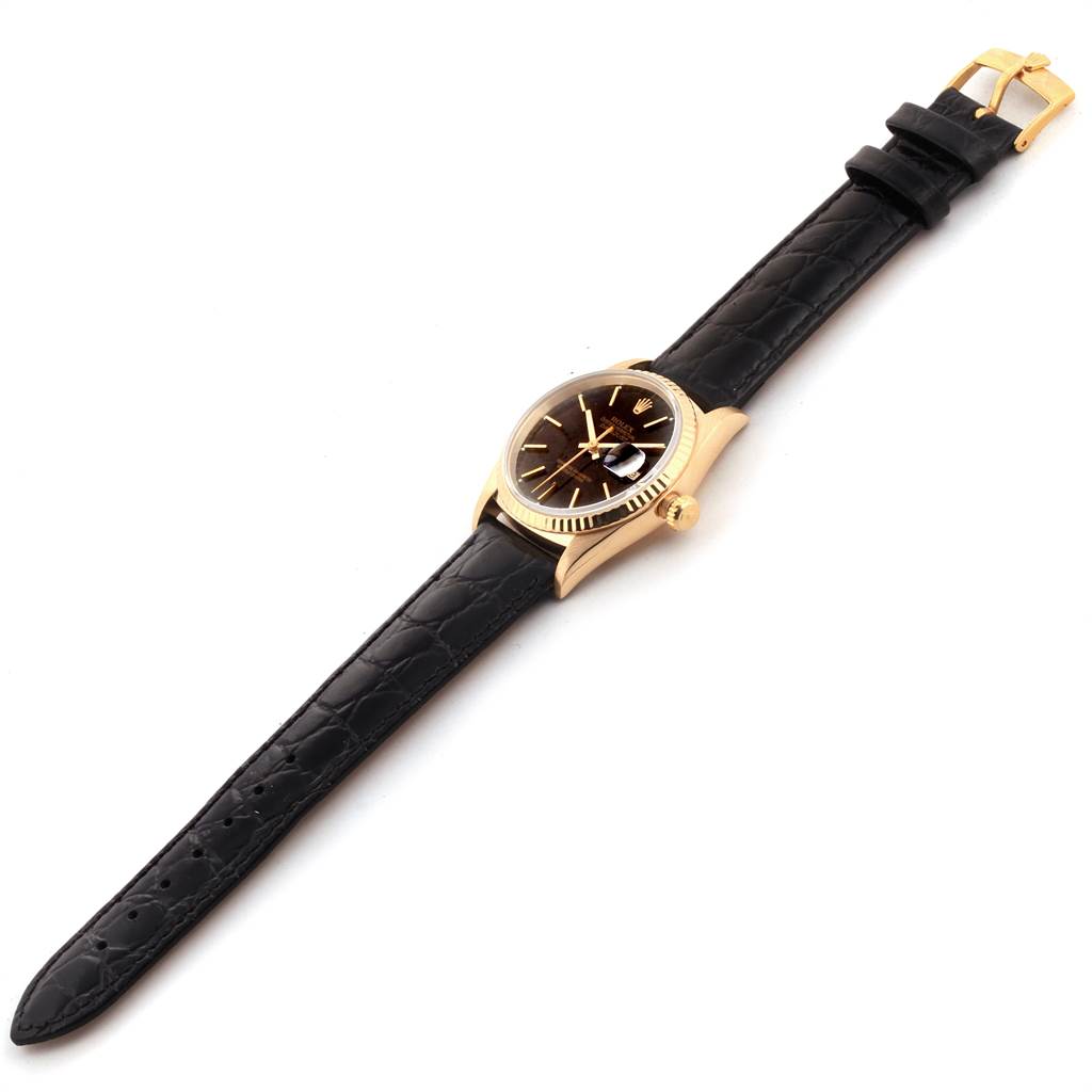 This image shows a Rolex Date 16238 Men's Yellow Gold Champagne Dial 16238 Men's Yellow Gold Champagne Dial model watch at an angled side view showcasing its black leather strap and gold casing.