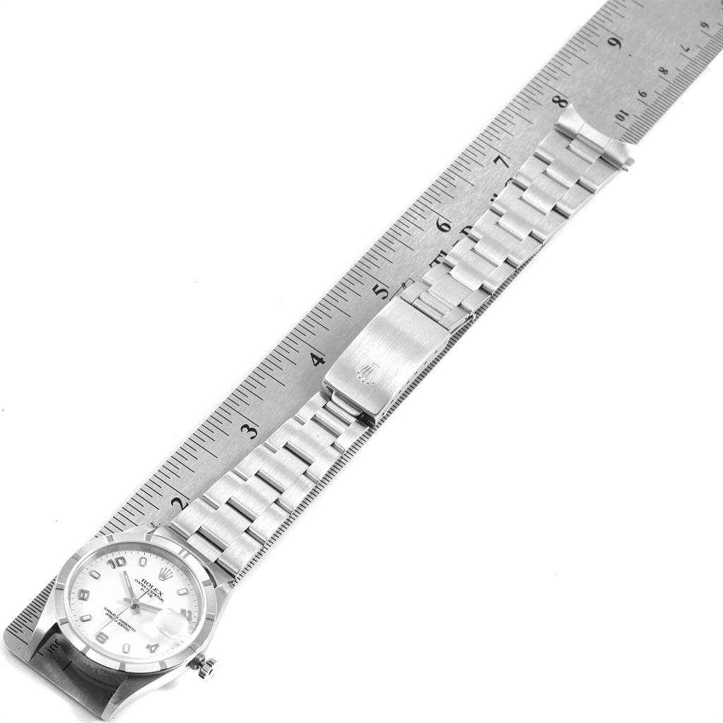 This image shows the full length of a Date model Rolex watch placed alongside a ruler for size reference.