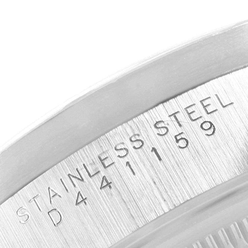 The image shows a close-up of the serial number and "Stainless Steel" engraving on the side of a Rolex Date 15210 Men's Stainless Steel White Dial 15210 Men's Stainless Steel White Dial model watch case.