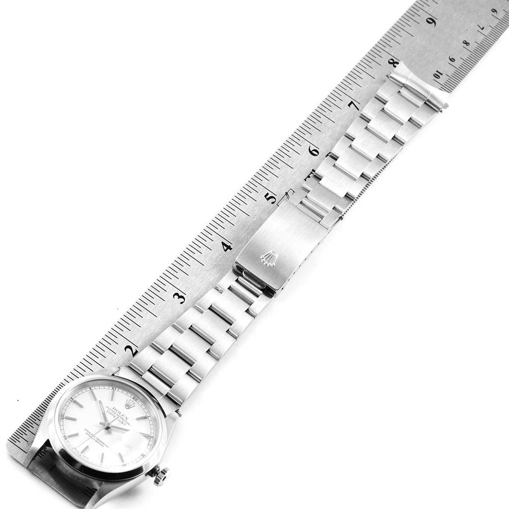 The image shows a Rolex Date 16200 Men's Stainless Steel White Dial 16200 Men's Stainless Steel White Dial watch with its stainless steel bracelet aligned next to a ruler.