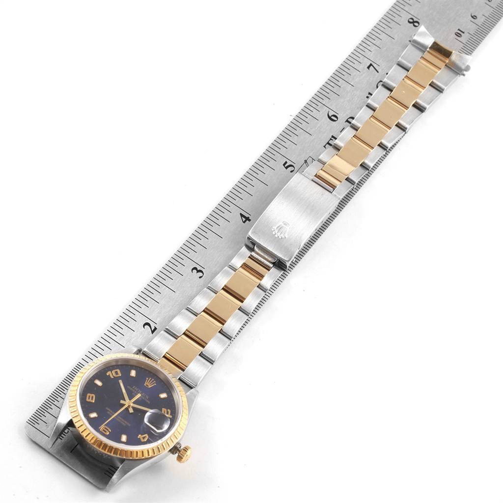 The image shows a Rolex Date 15223 Men's Steel and Gold (two tone) Blue Dial 15223 Men's Steel and Gold (two tone) Blue Dial model watch laid flat, highlighting the face, bracelet, and clasp against a ruler for scale.