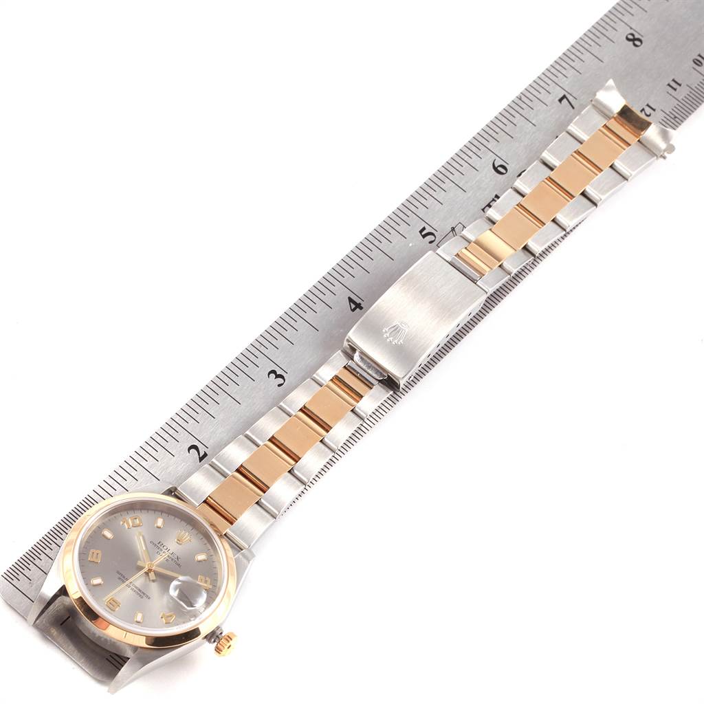 This image shows a Rolex Date 15203 Men's Steel and Gold (two tone) Grey Dial 15203 Men's Steel and Gold (two tone) Grey Dial watch angled flat, displaying its face, two-tone bracelet, and clasp alongside a ruler for scale.