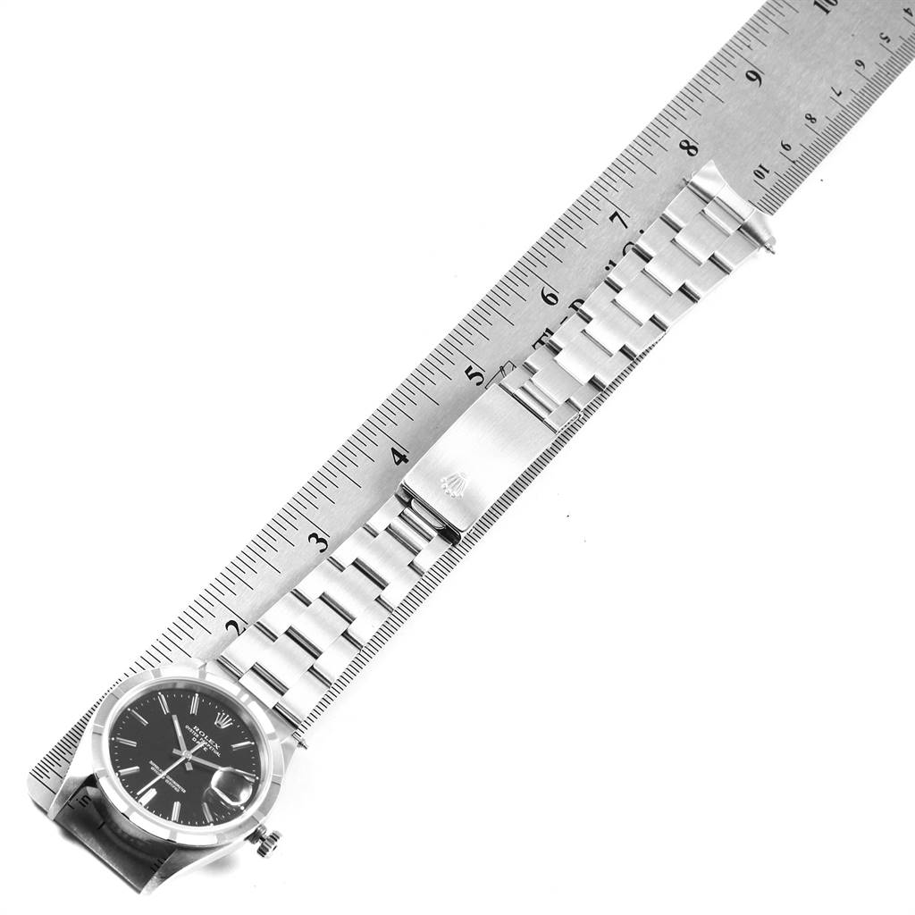 The image shows a Rolex Date 15210 Men's Stainless Steel Black Dial 15210 Men's Stainless Steel Black Dial model watch placed horizontally on a ruler, highlighting the bracelet and clasp.