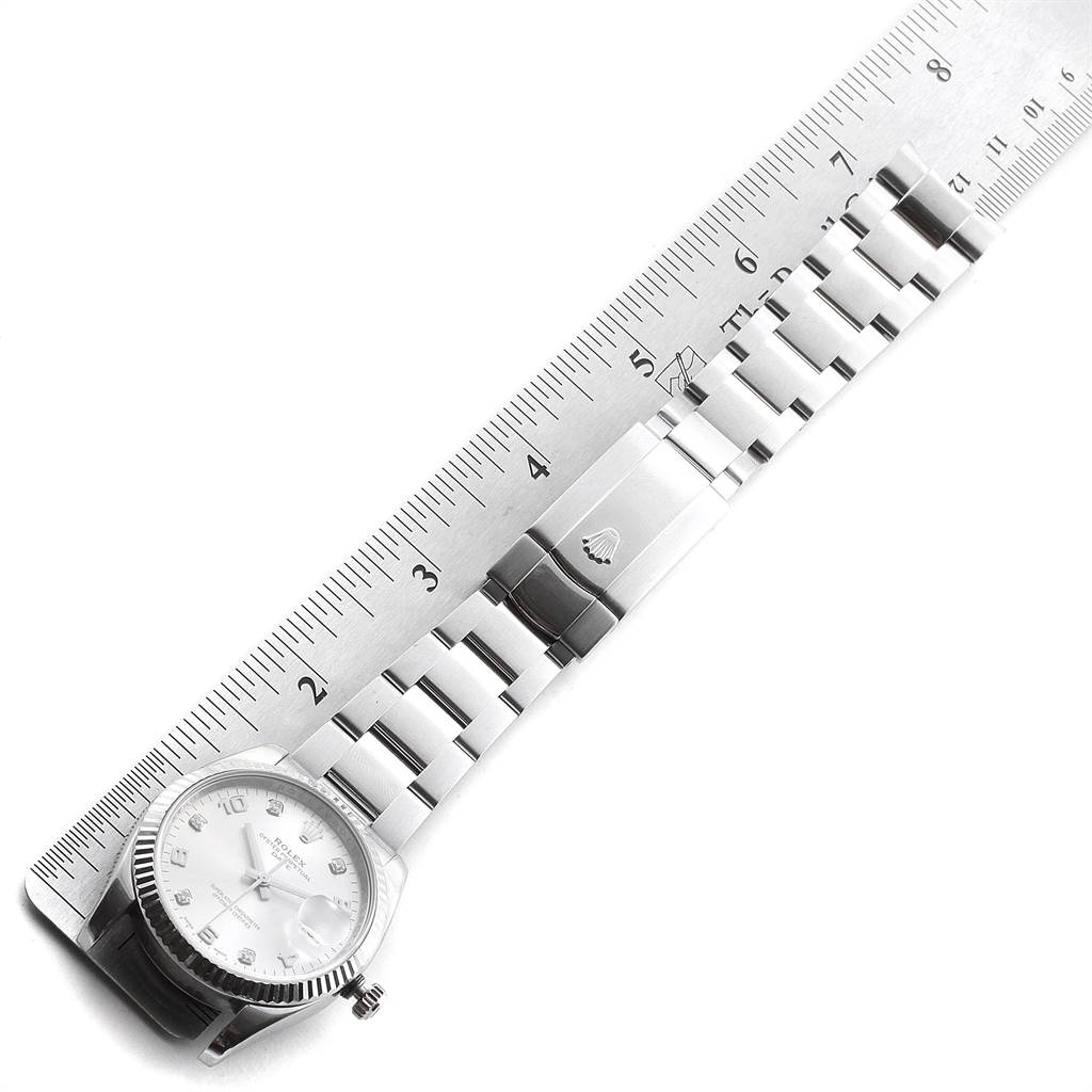 The image shows a Rolex Date 115234 Men's Stainless Steel Silver Dial 115234 Men's Stainless Steel Silver Dial watch laid flat next to a ruler, displaying the face, bracelet, and clasp.