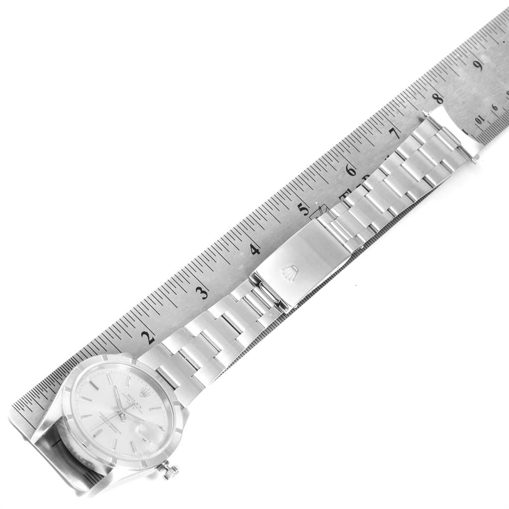 The Rolex Date 15210 Men's Stainless Steel Silver Dial 15210 Men's Stainless Steel Silver Dial model watch is shown from a top-down angle, featuring its face, bracelet, and clasp alongside a measuring ruler.
