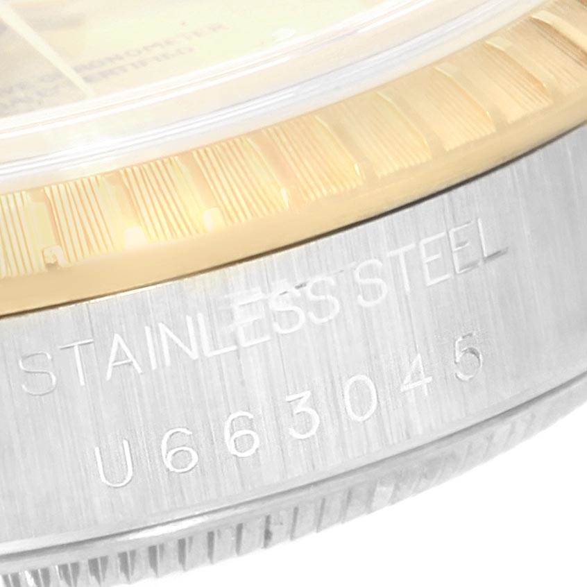 The image shows a close-up of the side view of the bezel and caseback of a Rolex Date 15223 Men's Steel and Gold (two tone) Champagne Dial 15223 Men's Steel and Gold (two tone) Champagne Dial model watch with "STAINLESS STEEL" engraved.