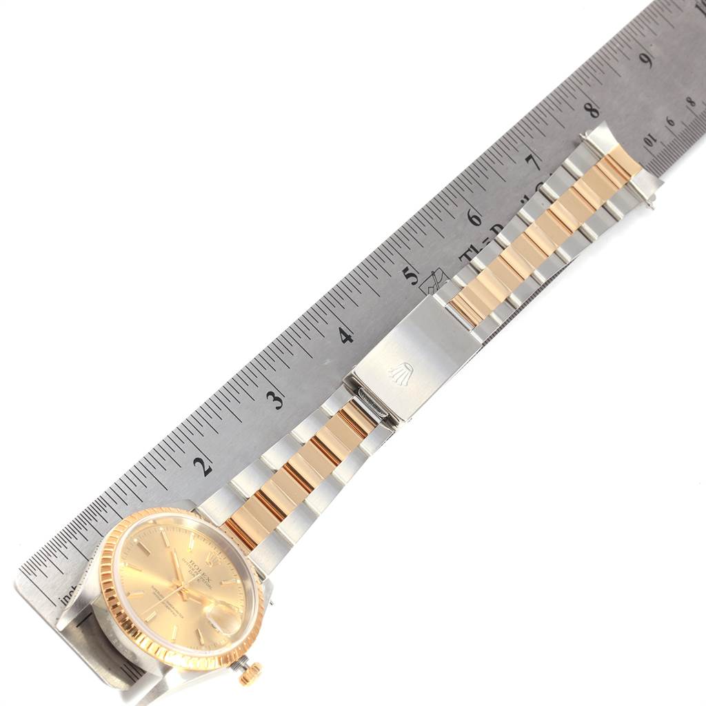 The image shows a Rolex Date 15223 Men's Steel and Gold (two tone) Champagne Dial 15223 Men's Steel and Gold (two tone) Champagne Dial model watch laid flat, with its face, bezel, and fully extended bracelet alongside a ruler.