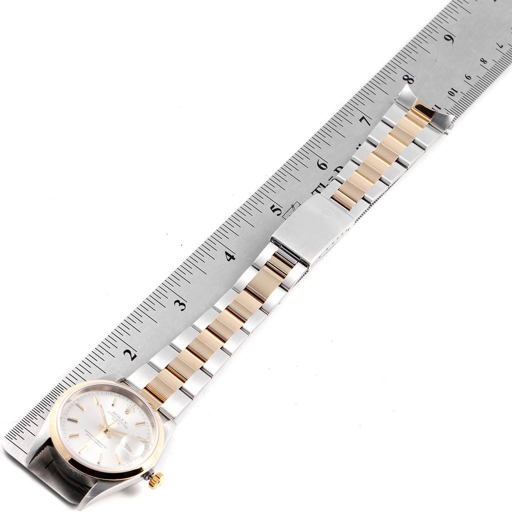 This image shows a Rolex Date 15203 Men's Steel and Gold (two tone) Silver Dial 15203 Men's Steel and Gold (two tone) Silver Dial model watch laid flat next to a ruler, displaying the face, bezel, band, and clasp.