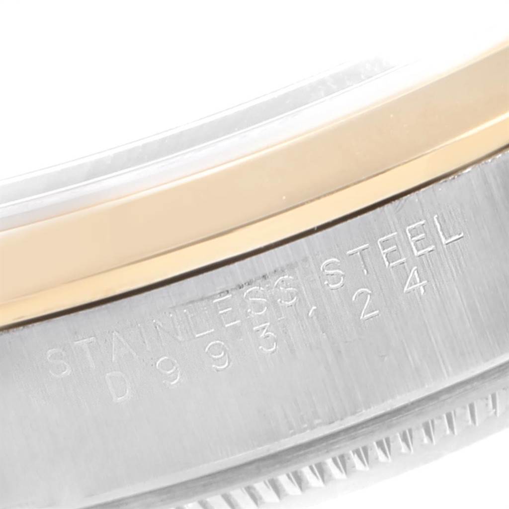 This image shows a close-up of the side of a stainless steel Rolex Date 15203 Men's Steel and Gold (two tone) Silver Dial 15203 Men's Steel and Gold (two tone) Silver Dial watch, featuring part of the bezel and engraved serial number.