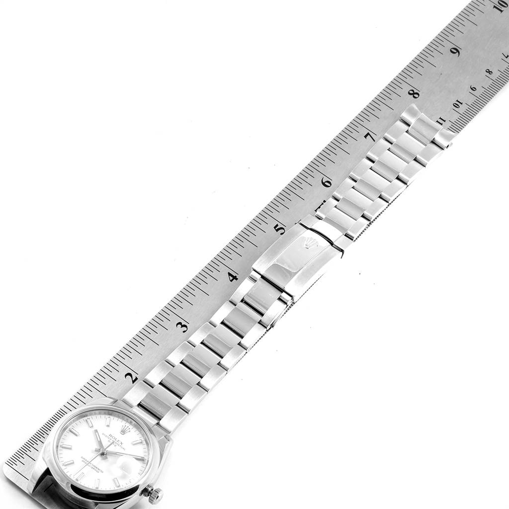 The image shows a Rolex Date 115200 Men's Stainless Steel White Dial 115200 Men's Stainless Steel White Dial model watch laid flat beside a ruler, displaying the face, band, and clasp.