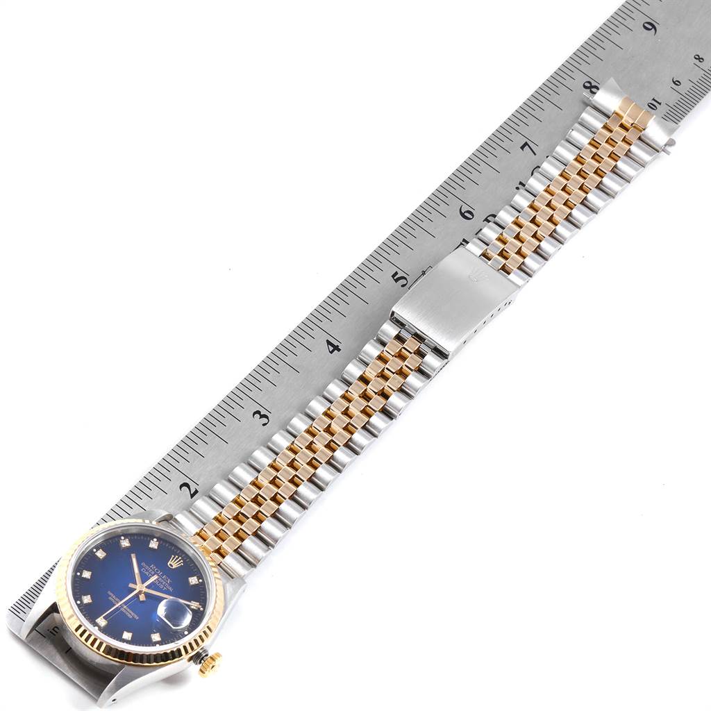 This image shows a Rolex Date 16233 Men's Steel and Gold (two tone) Blue Dial 16233 Men's Steel and Gold (two tone) Blue Dial model watch from a top-down angle, highlighting its face, bezel, and two-tone bracelet with a ruler measuring its length.