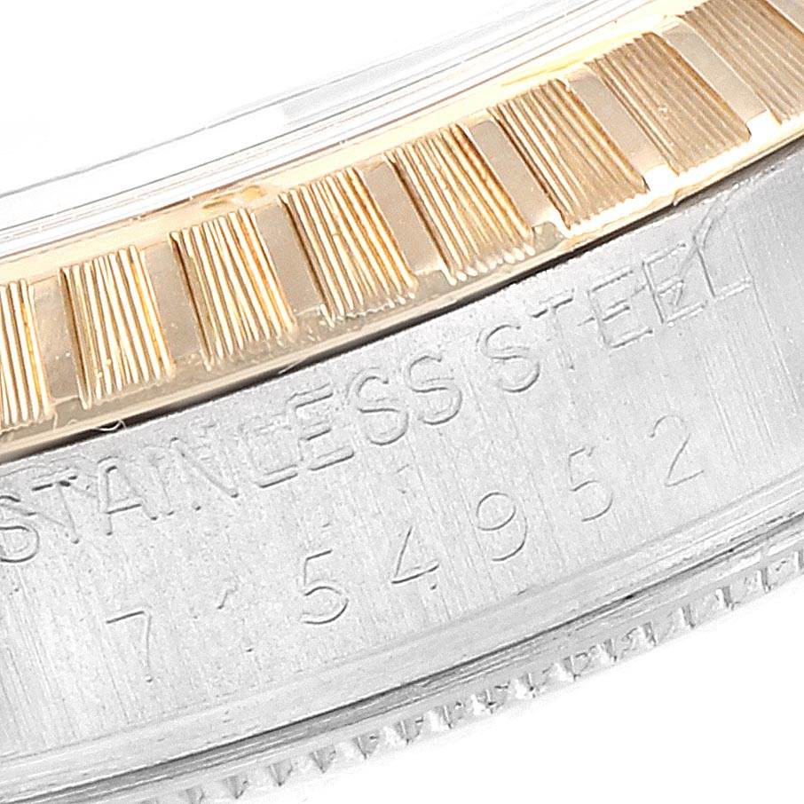 This close-up image of a Rolex Date 15053 Men's Steel and Gold (two tone) Silver Dial 15053 Men's Steel and Gold (two tone) Silver Dial model watch shows part of the fluted bezel and part of the stainless steel case with an engraving.