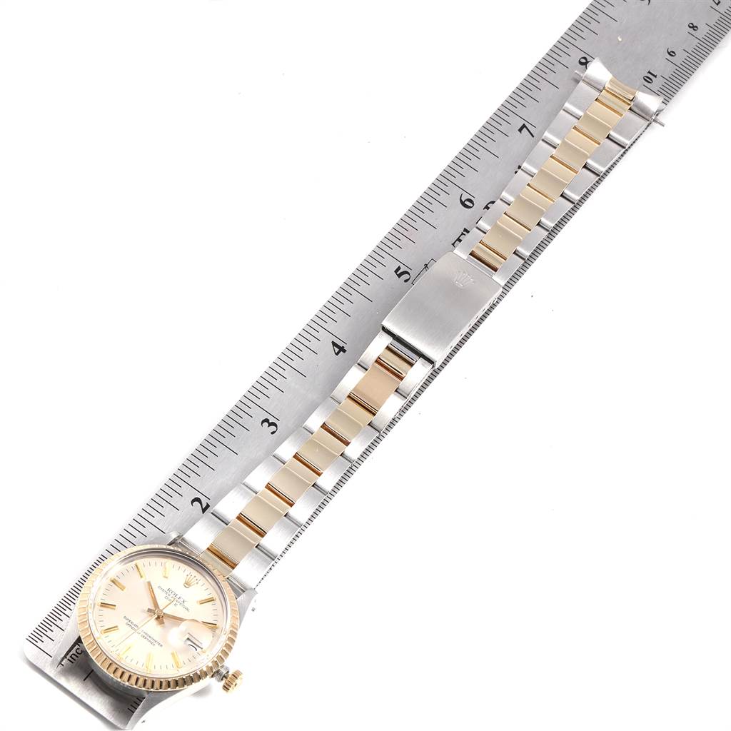 The image shows a Rolex Date 15053 Men's Steel and Gold (two tone) Silver Dial 15053 Men's Steel and Gold (two tone) Silver Dial model watch laid flat alongside a ruler, displaying its face, bracelet, and clasp.